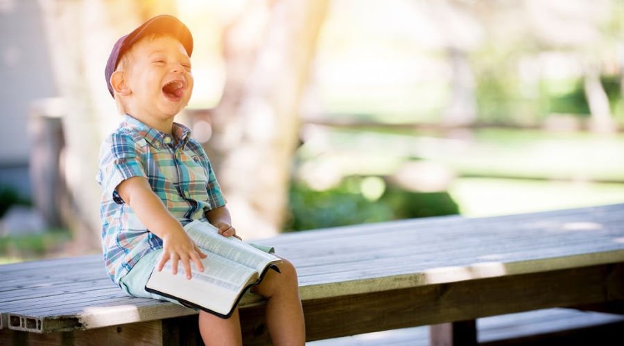 Small child laughing on a bench in a park